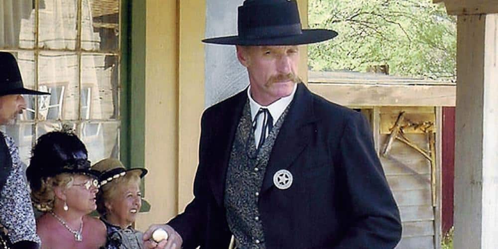 Wyatt Earp the actor dressed as Wyatt Earp in black suit, hat and stopwatch