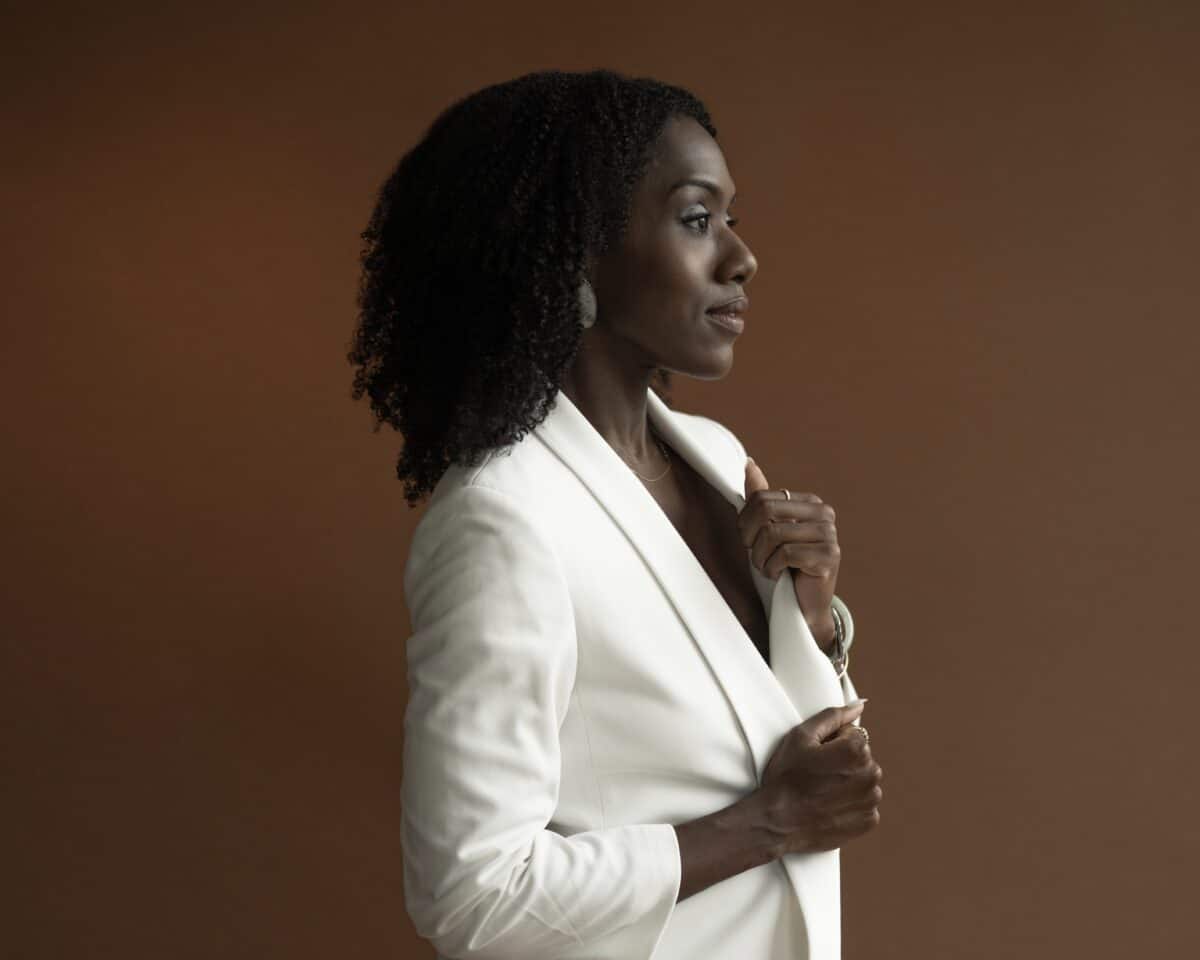 Alicia Waller stands in profile in a white blazer