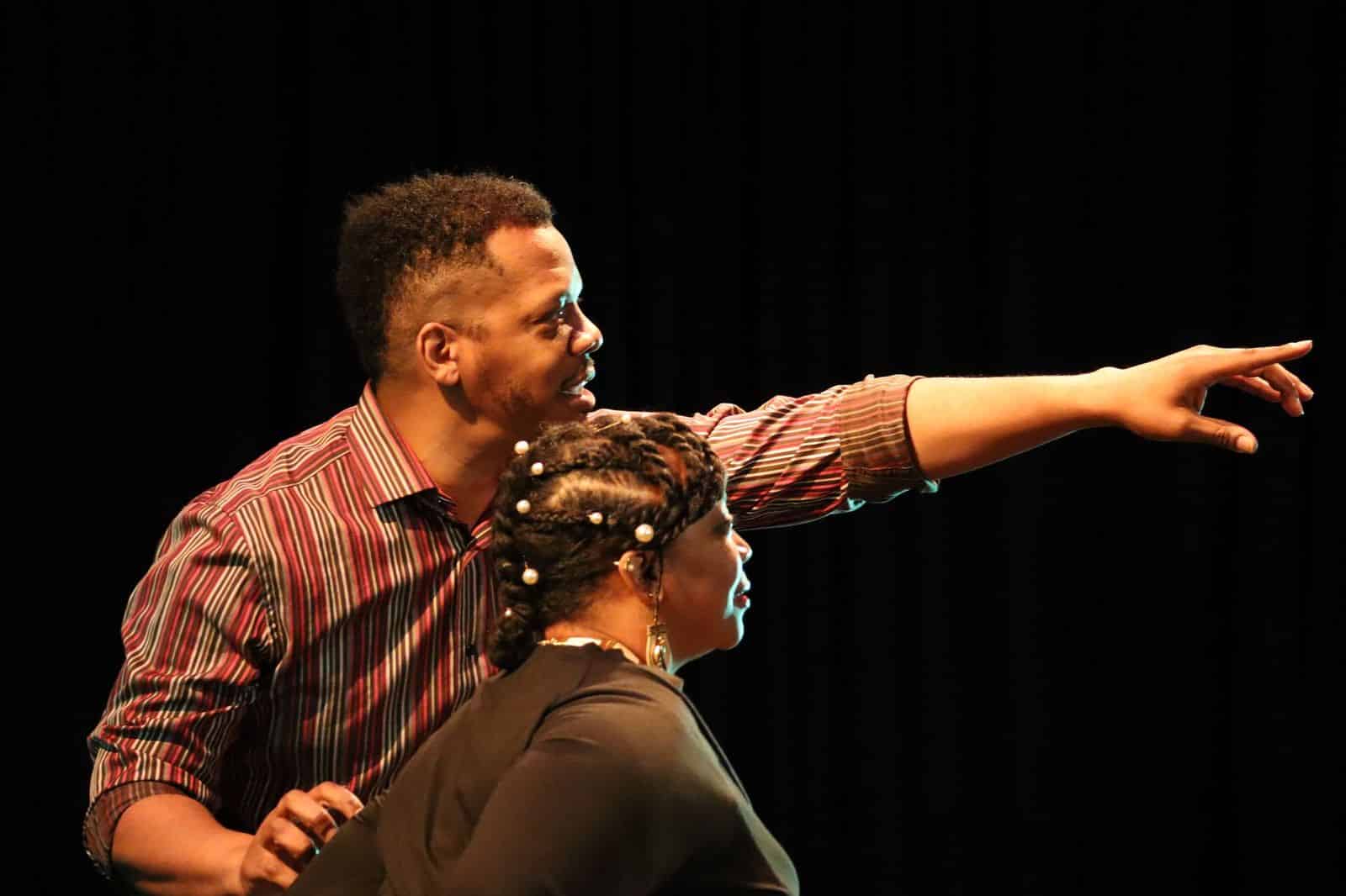 A man and woman are pointing at an object, appearing engaged in conversation and sharing their observations.