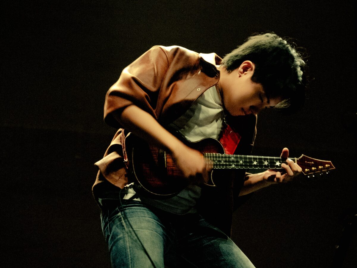 A man engaged in playing a ukulele on stage, showcasing his musical talent.