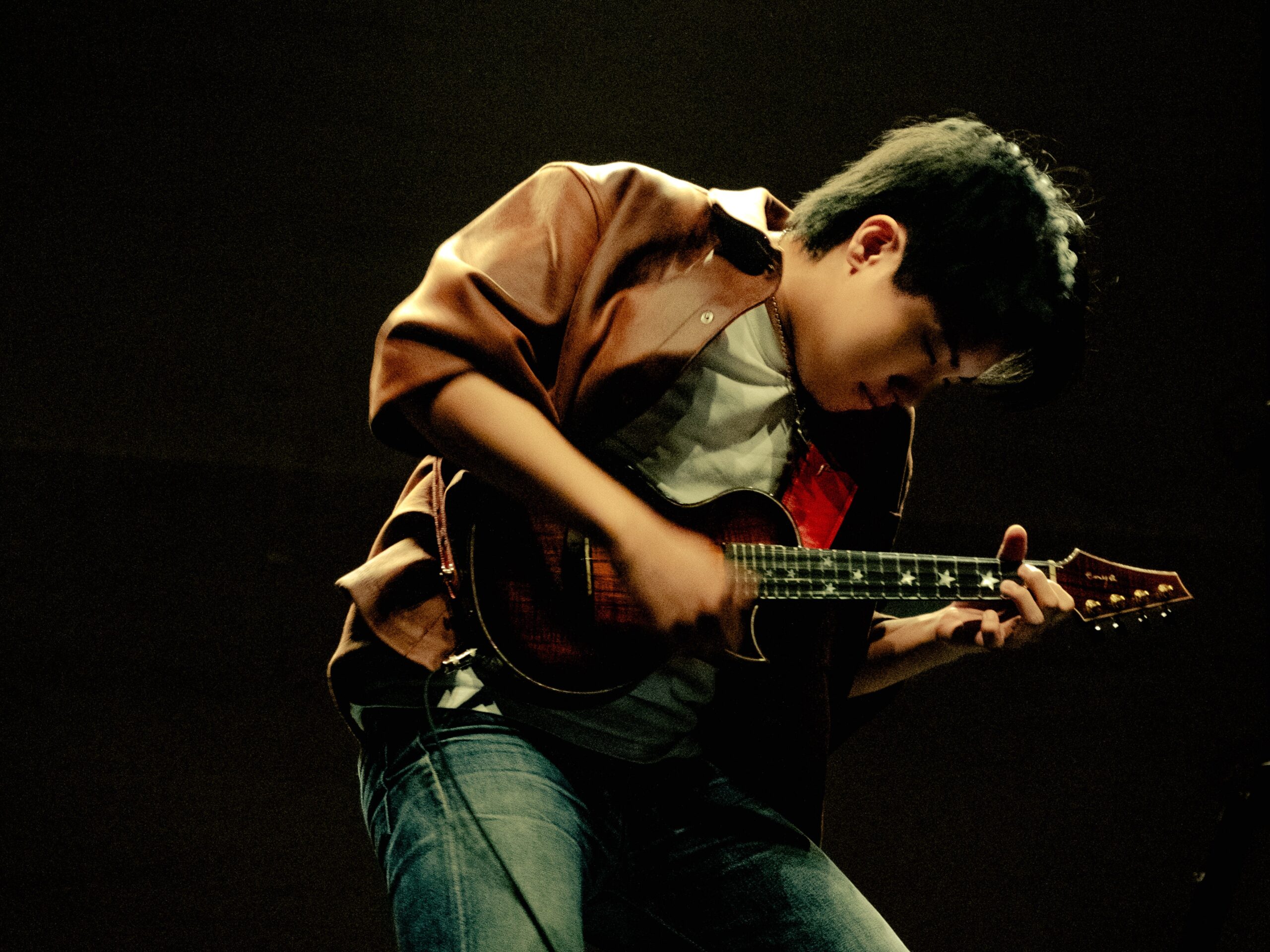 A man engaged in playing a ukulele on stage, showcasing his musical talent.